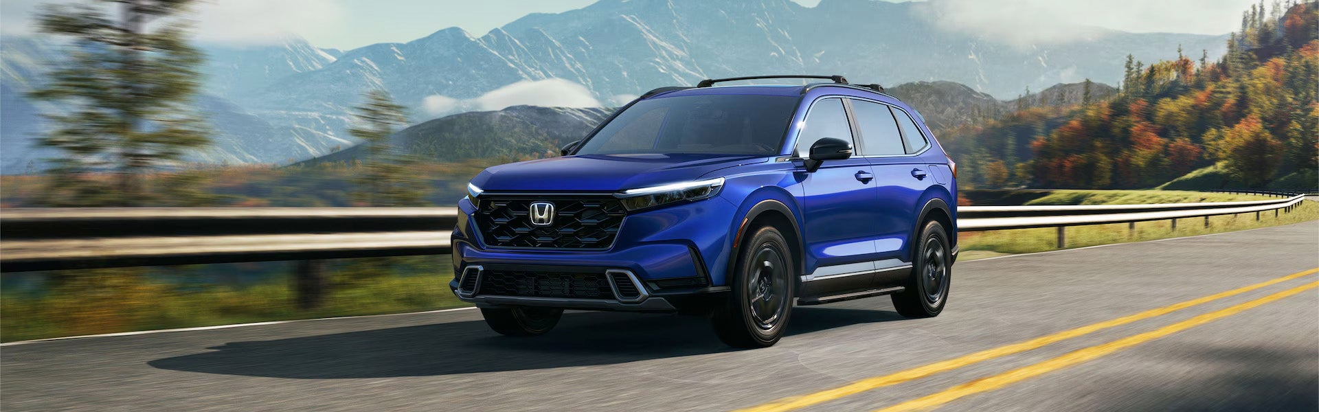 Blue SUV driving on a mountain road with autumn foliage, mountains in the blurry background.
