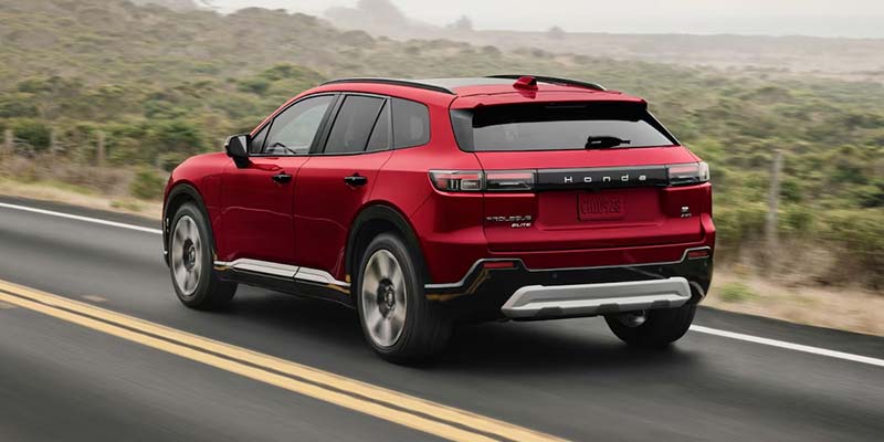 Red Honda Prologue electric SUV seen from the rear on a road.