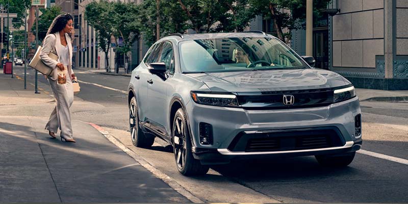 Gray Honda Prologue electric SUV with a woman approaching it.