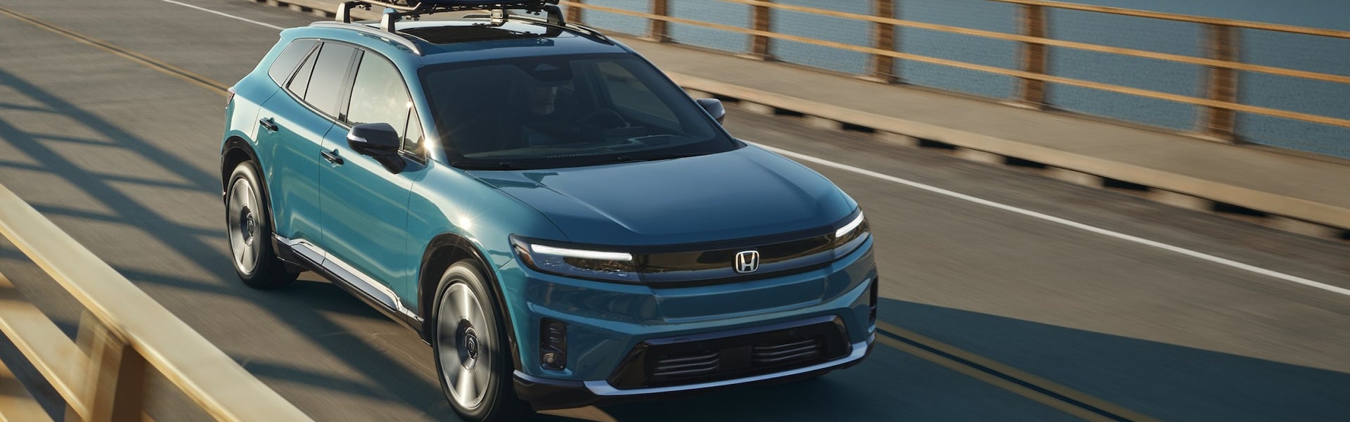 Blue Honda Prologue electric SUV driving on a bridge